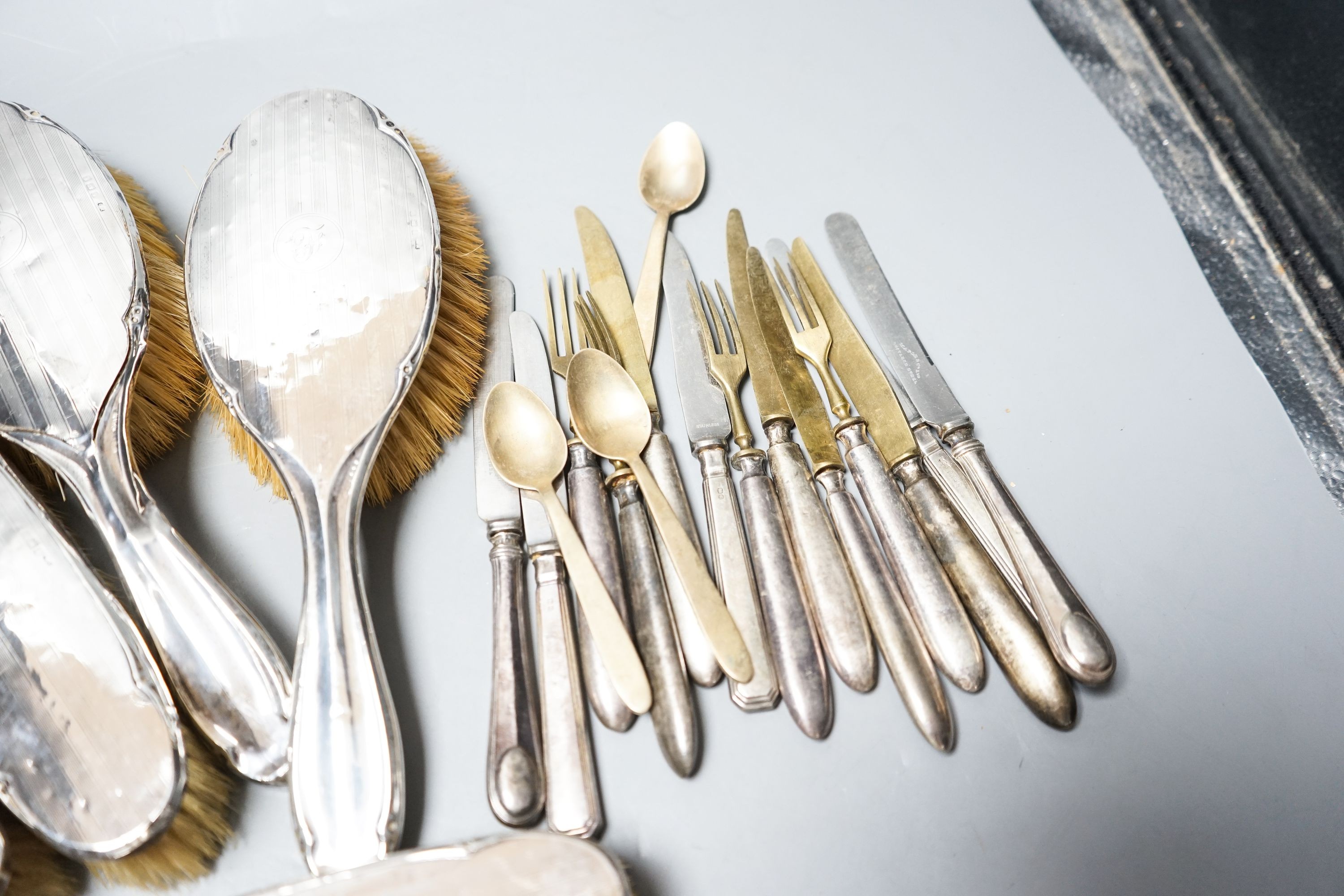 Six assorted silver mounted clothes and hair brushes and a small group of sterling handled cutlery.